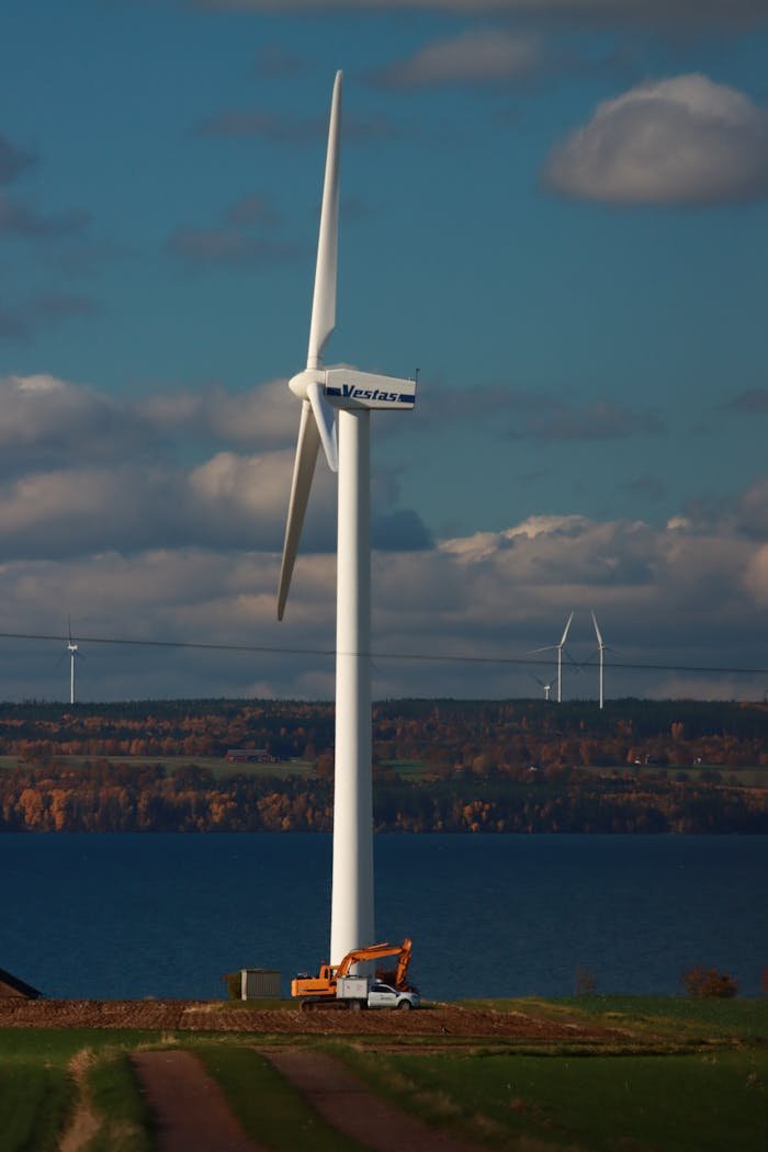 Wind turbine in a rural landscape with lake view showcasing renewable energy and sustainability.